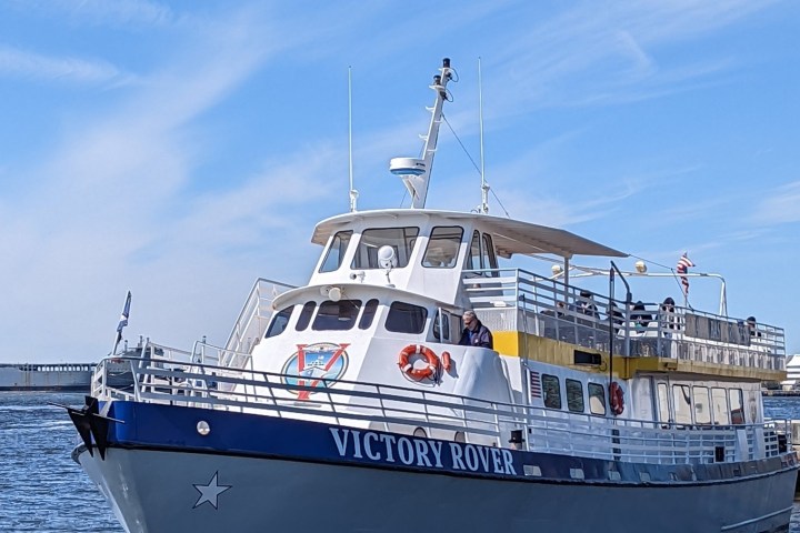 A ferry boat named Victory Rover docked at a pier under a clear blue sky.